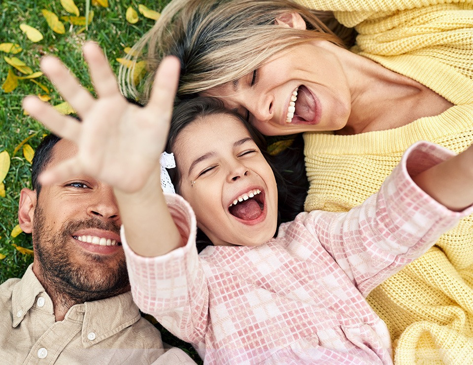A family laying on the ground smiling